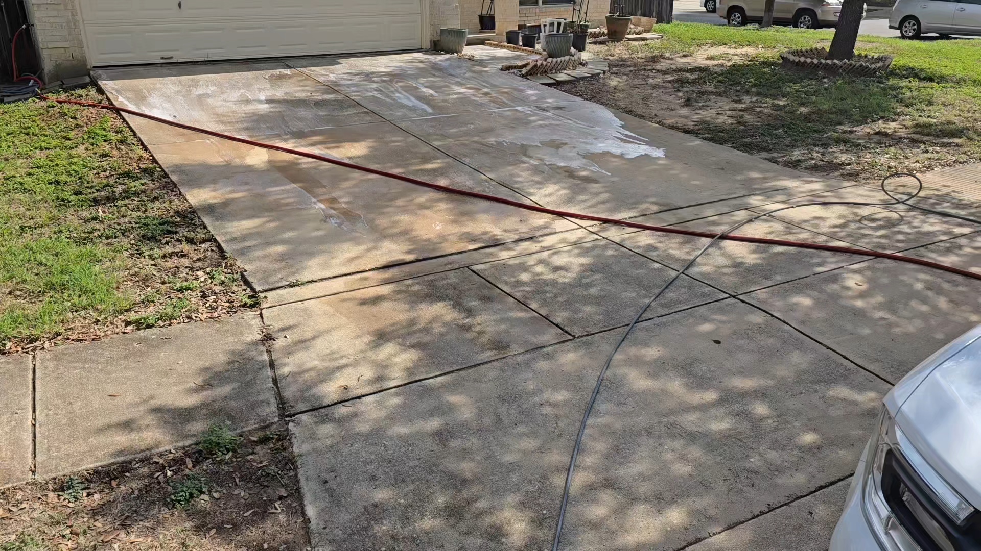 Heavily stained concrete driveway showing oil stains and discoloration before power washing